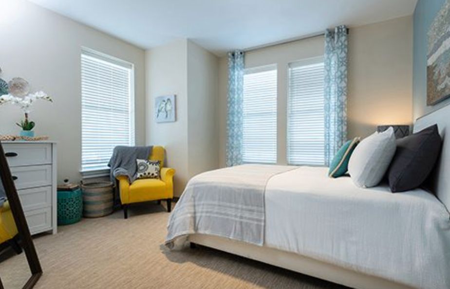 A cozy bedroom with a comfortable bed and a yellow armchair near the window.