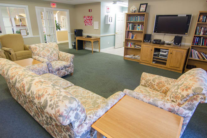 A cozy living room with floral sofas, a television, and a bookshelf.