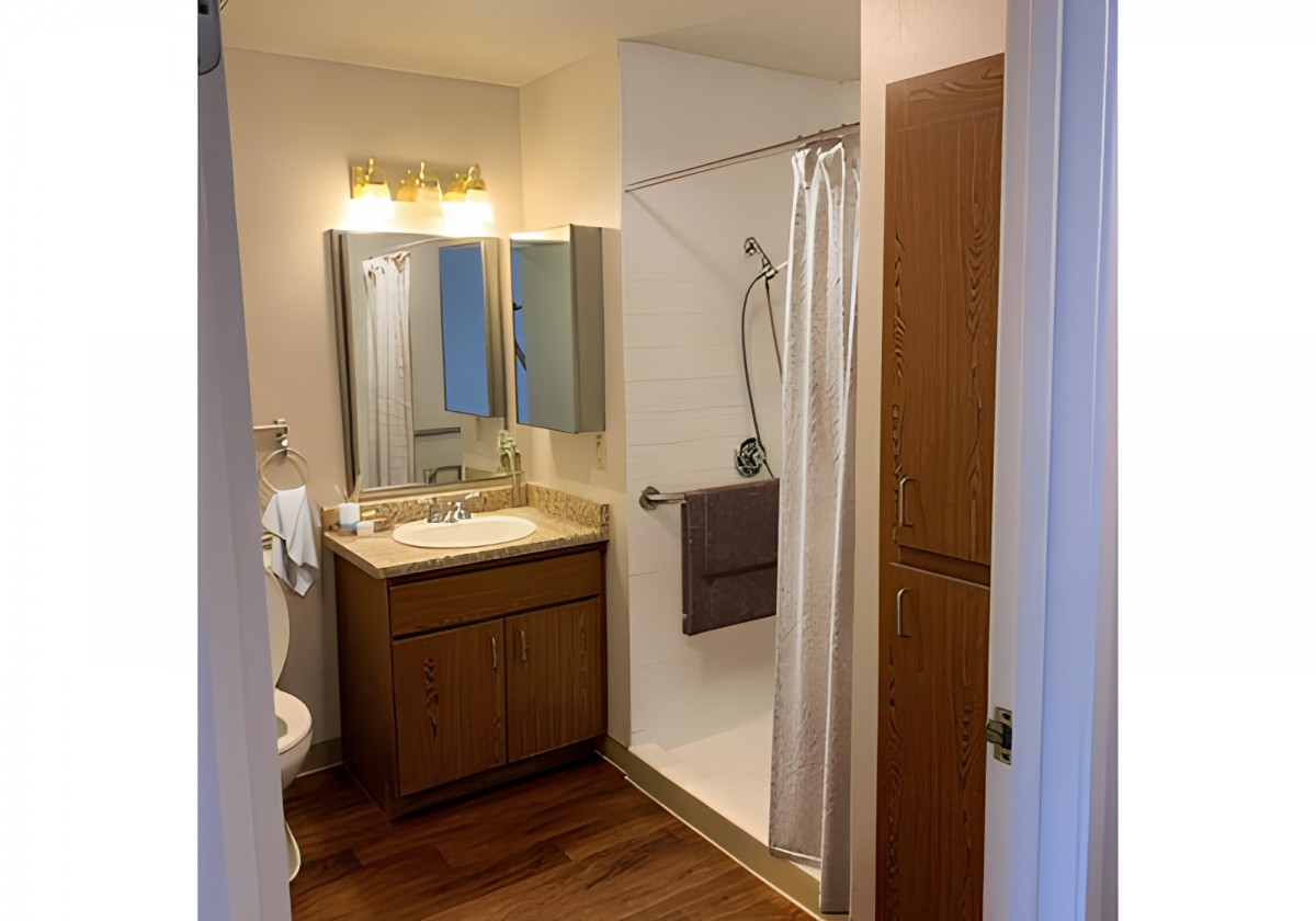 A modern bathroom with a shower, sink, and storage cabinets.