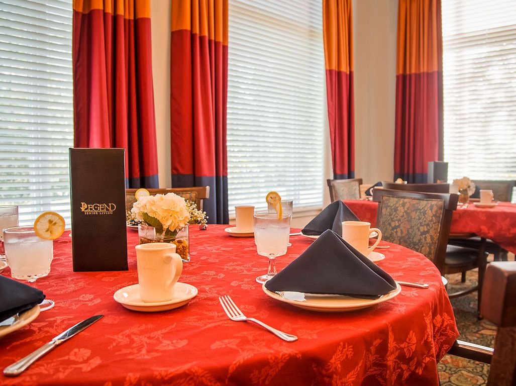 An elegantly set dining table with a red tablecloth and black napkins in a restaurant.