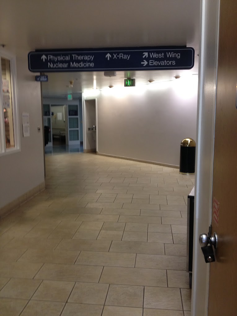 A hospital hallway with directional signage overhead.