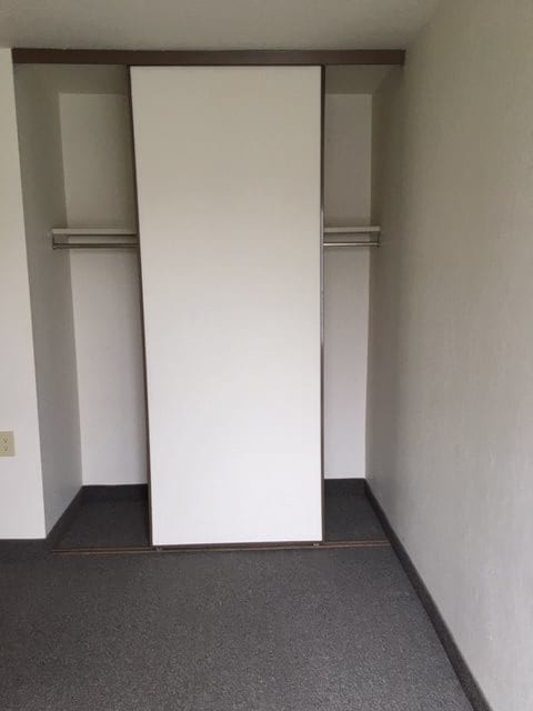 An empty minimalist closet with a sliding door and hanging rod.
