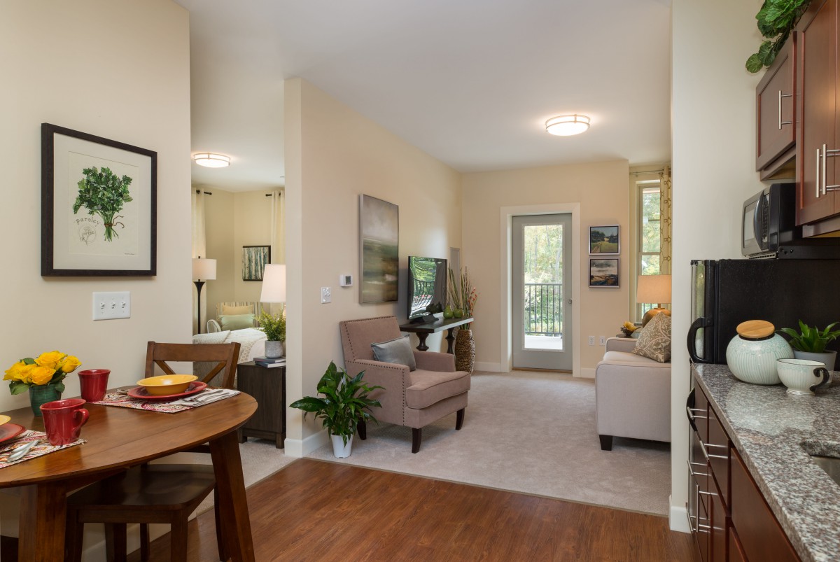 A cozy living room with a dining area, featuring modern furniture and natural lighting.