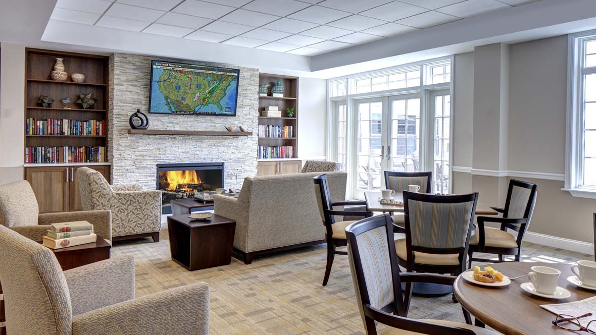 A cozy living room featuring a fireplace, comfortable seating, a wall-mounted television, and large windows.