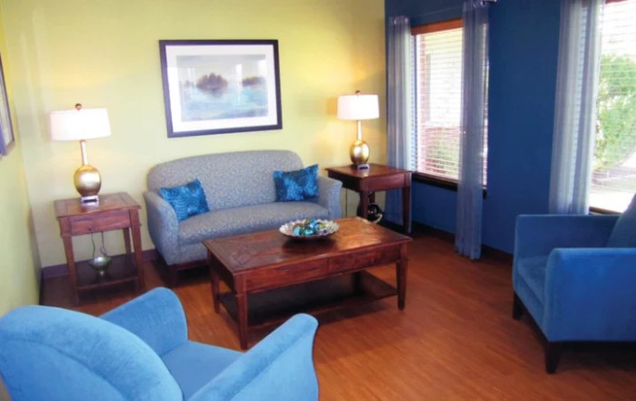 A cozy living room with blue furniture and a wooden floor.