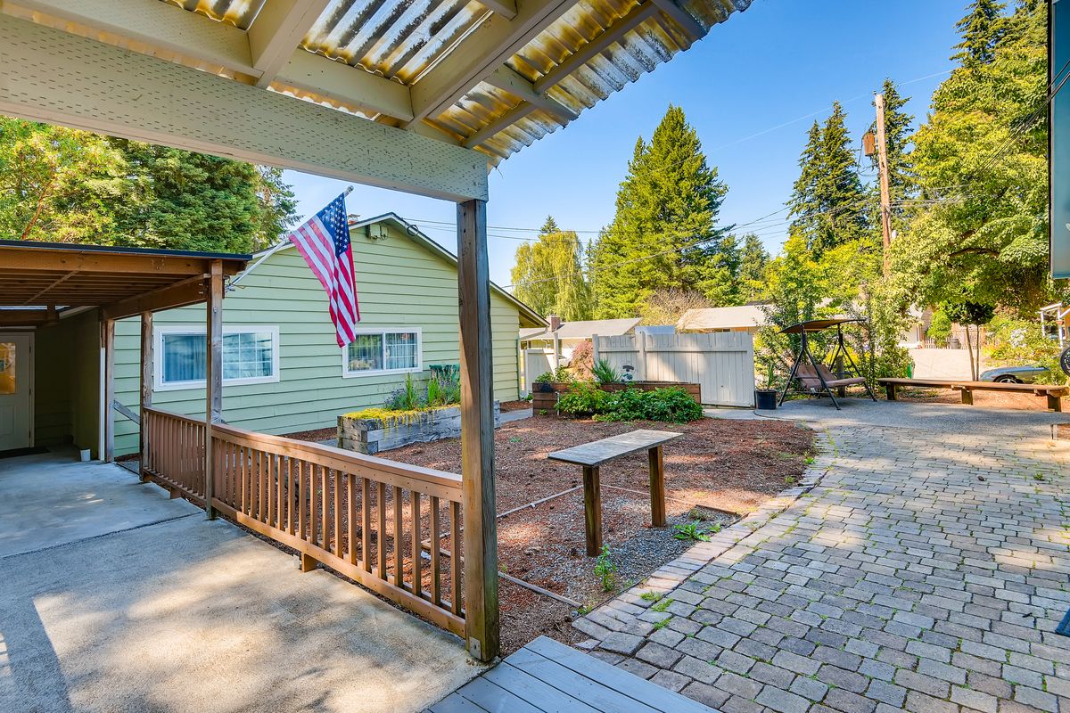 A sunny backyard with a patio, garden area, and an American flag.