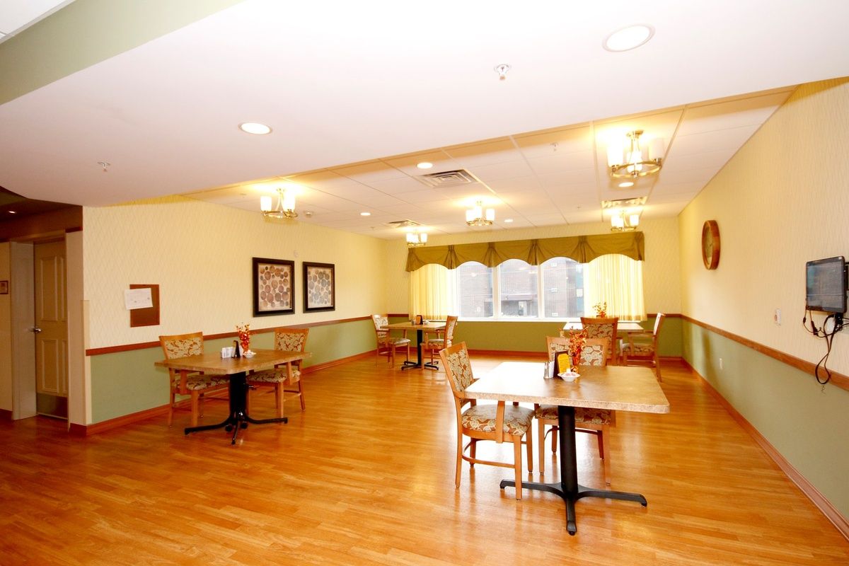 A well-lit dining area with wooden floors, several tables and chairs, and decorative elements on the walls.
