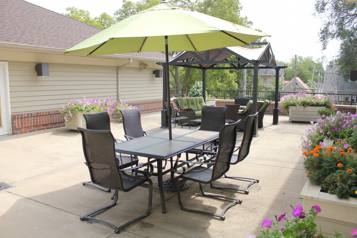 An outdoor patio area with furniture, including a table, chairs, and an umbrella.