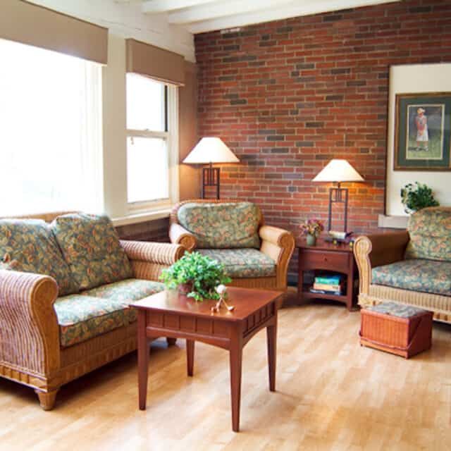 A cozy living room with a brick accent wall, featuring a sofa set, coffee table, and floor lamps.
