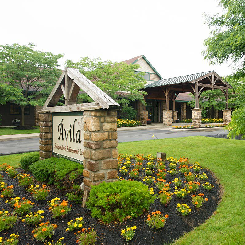 A scenic entrance to a resort featuring a well-maintained garden and stone signage.