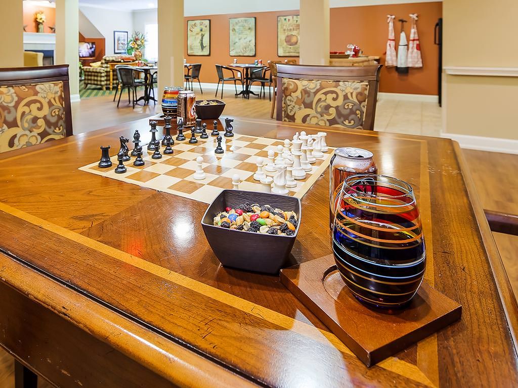 A cozy game room featuring a chess set on a polished wooden table, surrounded by decorative elements.