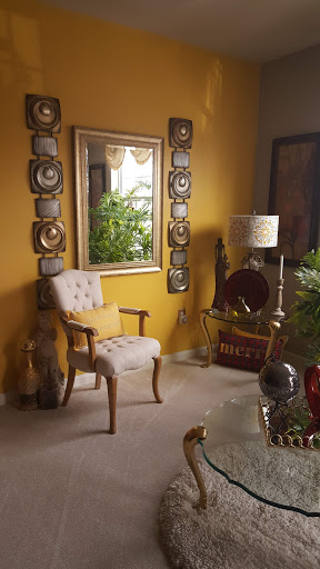 A cozy living room corner featuring a stylish chair, decorative mirror, and vibrant yellow walls.