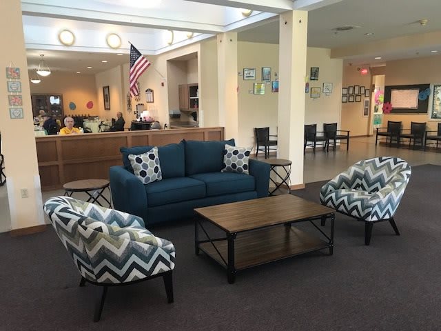 A lobby with a comfortable seating area featuring a sofa, armchairs, and a coffee table.