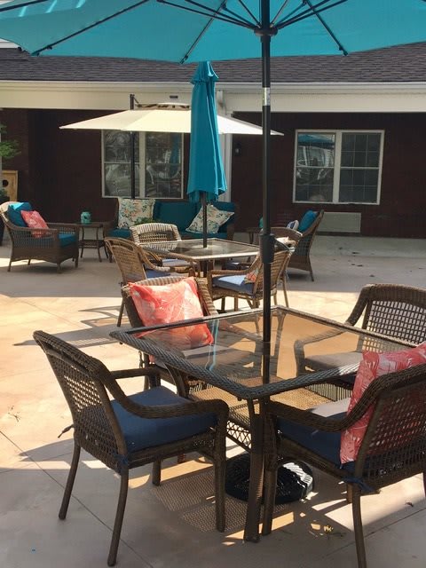A sunny outdoor patio featuring tables and chairs with colorful cushions and umbrellas.