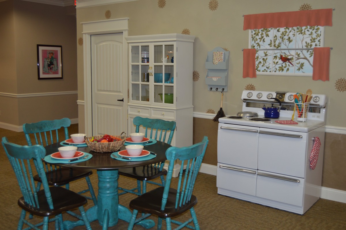A cozy vintage kitchen and dining area with turquoise chairs, a dark wooden table set for a meal, and a white stove.
