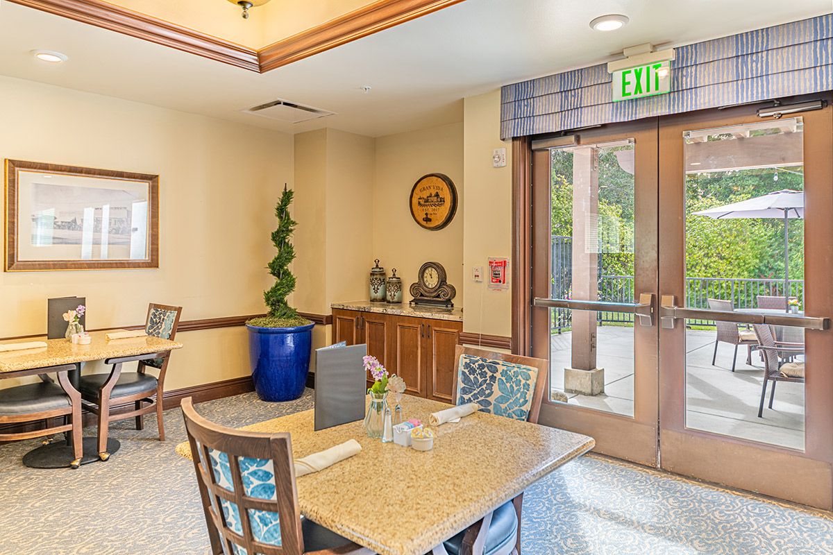 A cozy dining area with a table set, decorative plants, and natural light streaming through the glass door.