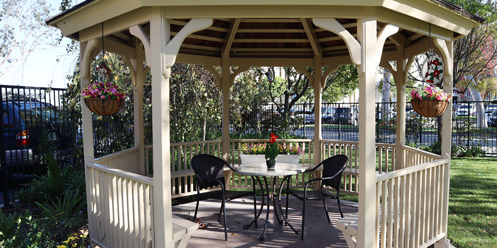 An inviting gazebo with a table and chairs set in a tranquil garden setting.