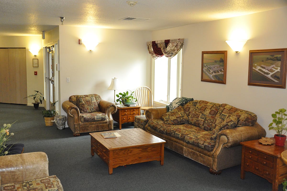 A cozy living room with patterned sofas, an armchair, and a wooden coffee table.
