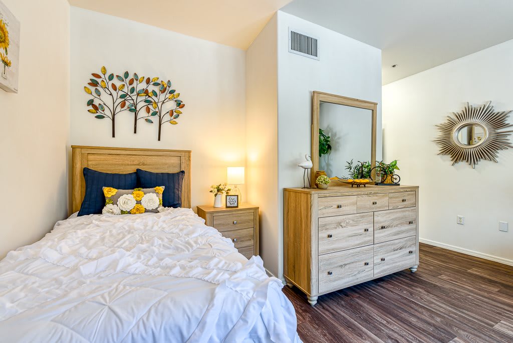 A cozy bedroom with a wooden dresser and bed, complemented by stylish decor and soft lighting.
