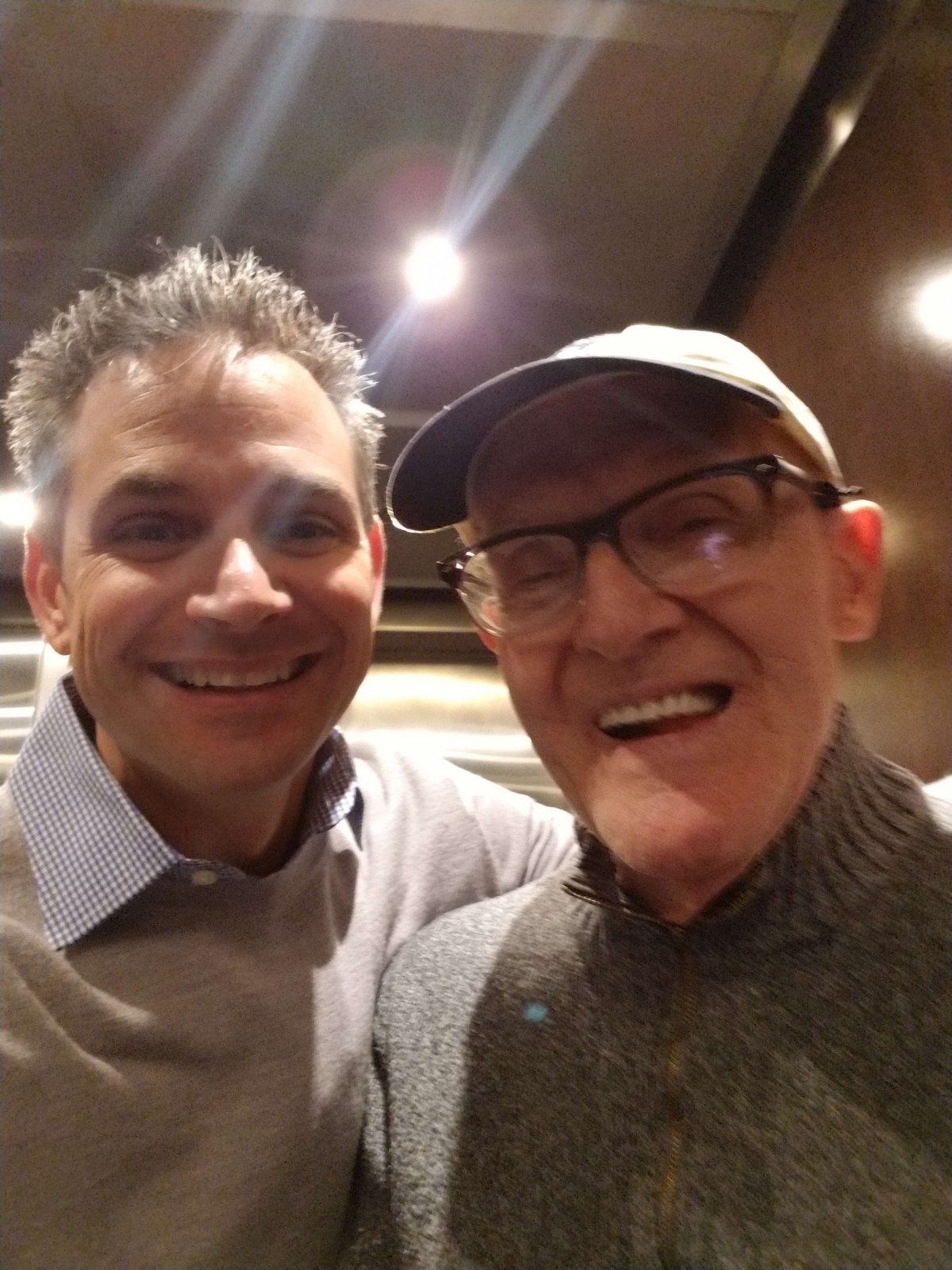 Two people taking a selfie indoors, both smiling.