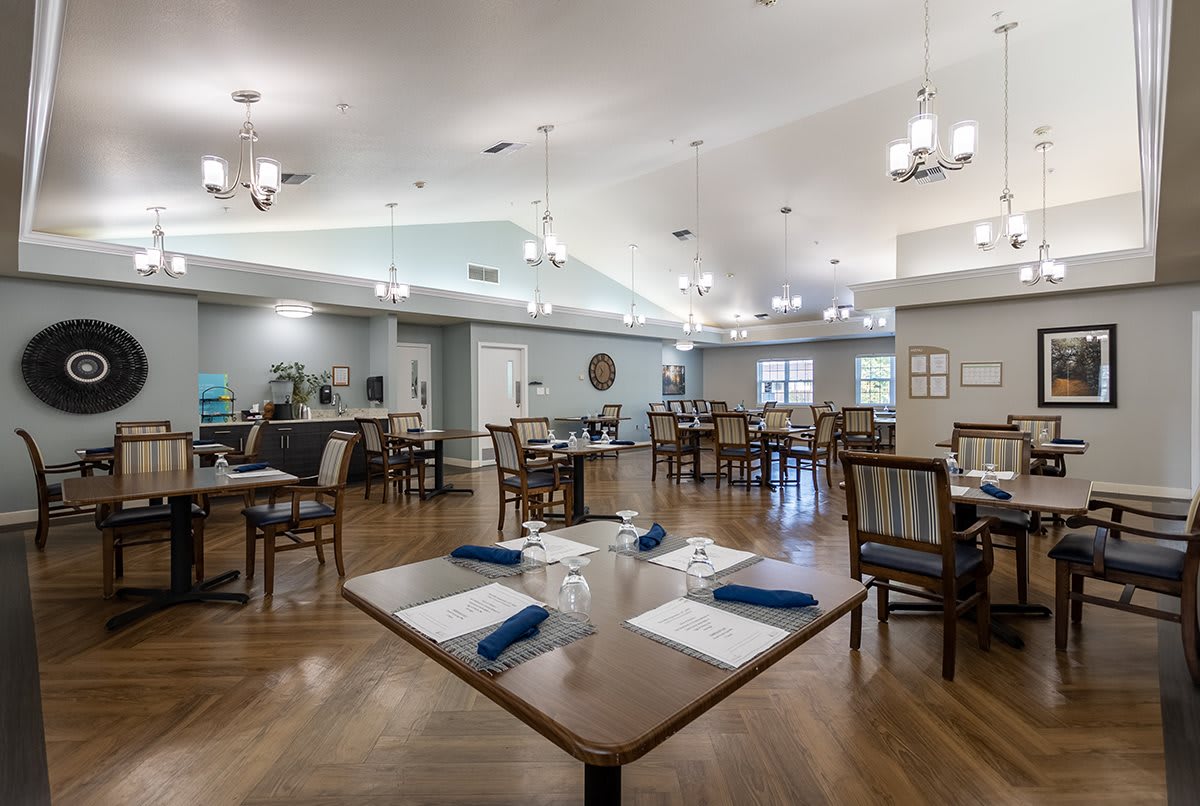 A spacious dining area with neatly arranged tables, chairs, and elegant chandeliers.