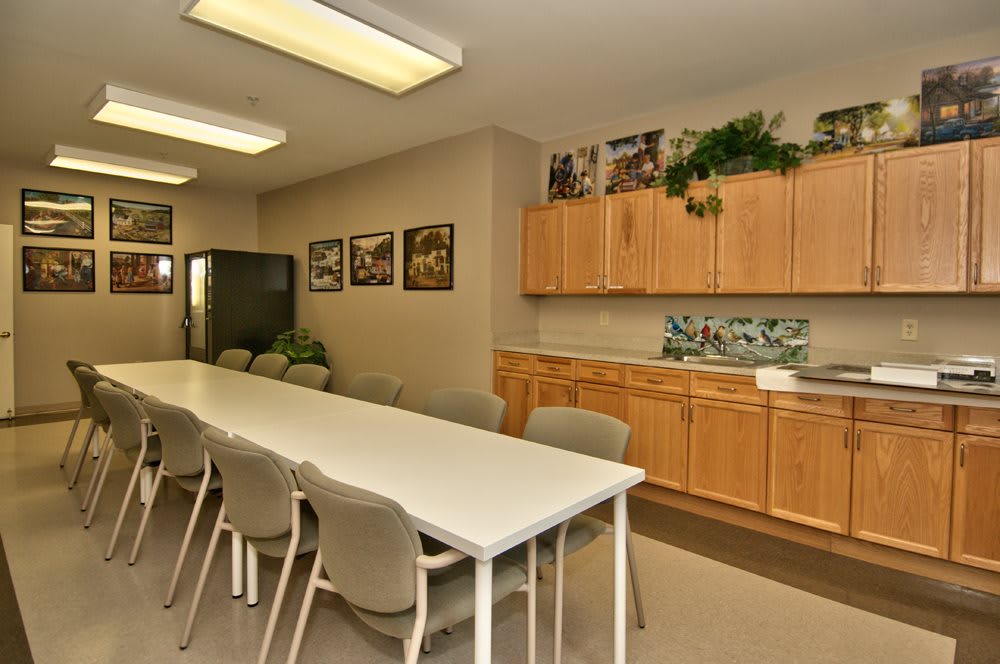 A well-lit conference room with a long table, several chairs, and cabinetry along the wall.