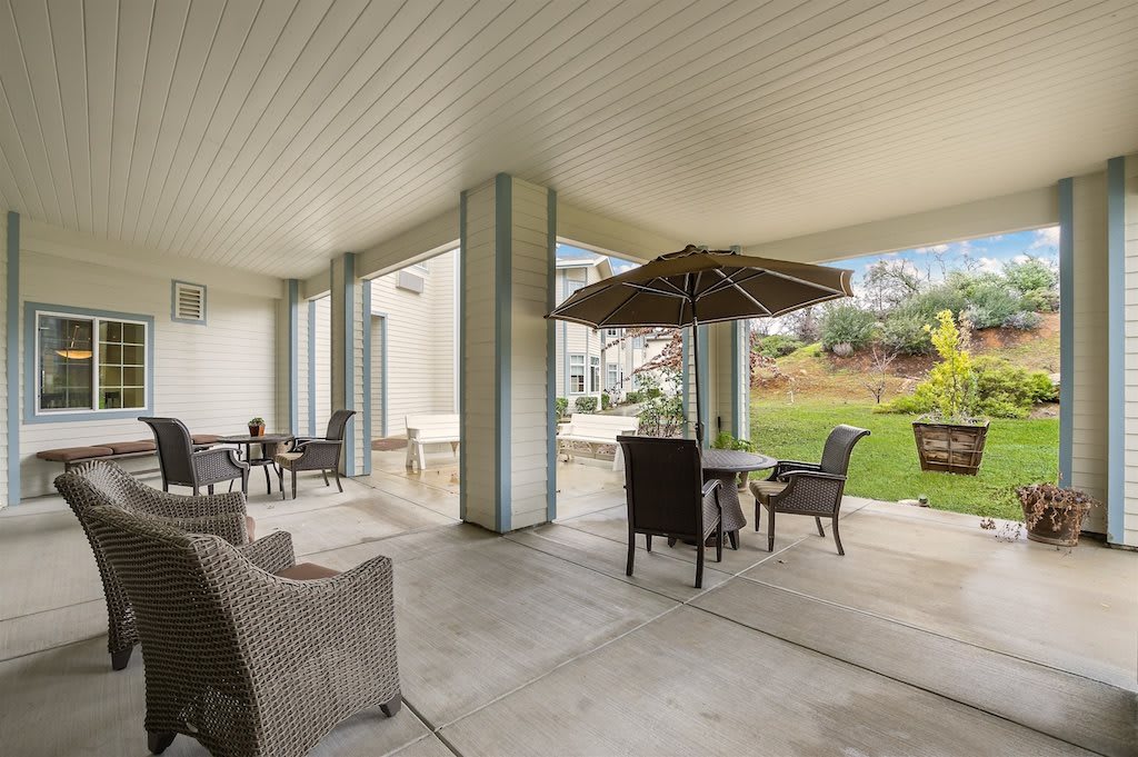 A spacious covered patio with outdoor seating and garden views.