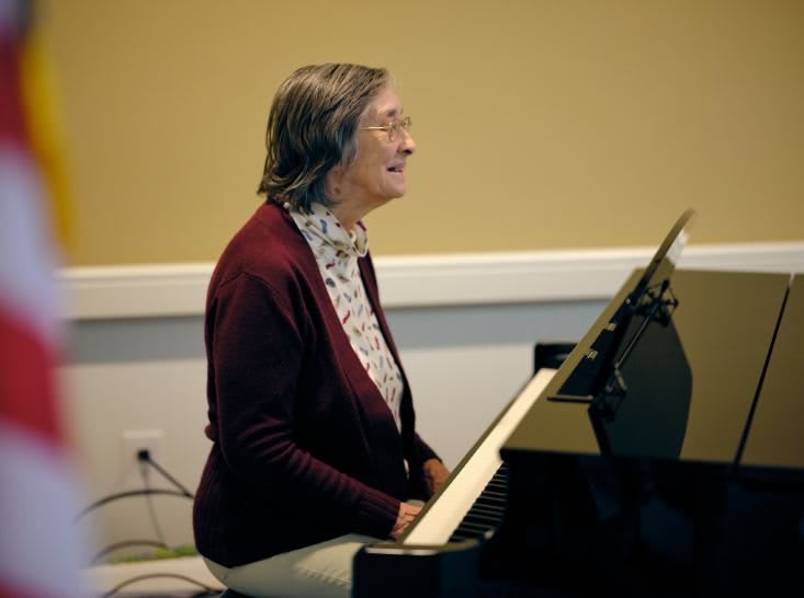 An elderly woman playing the piano indoors.