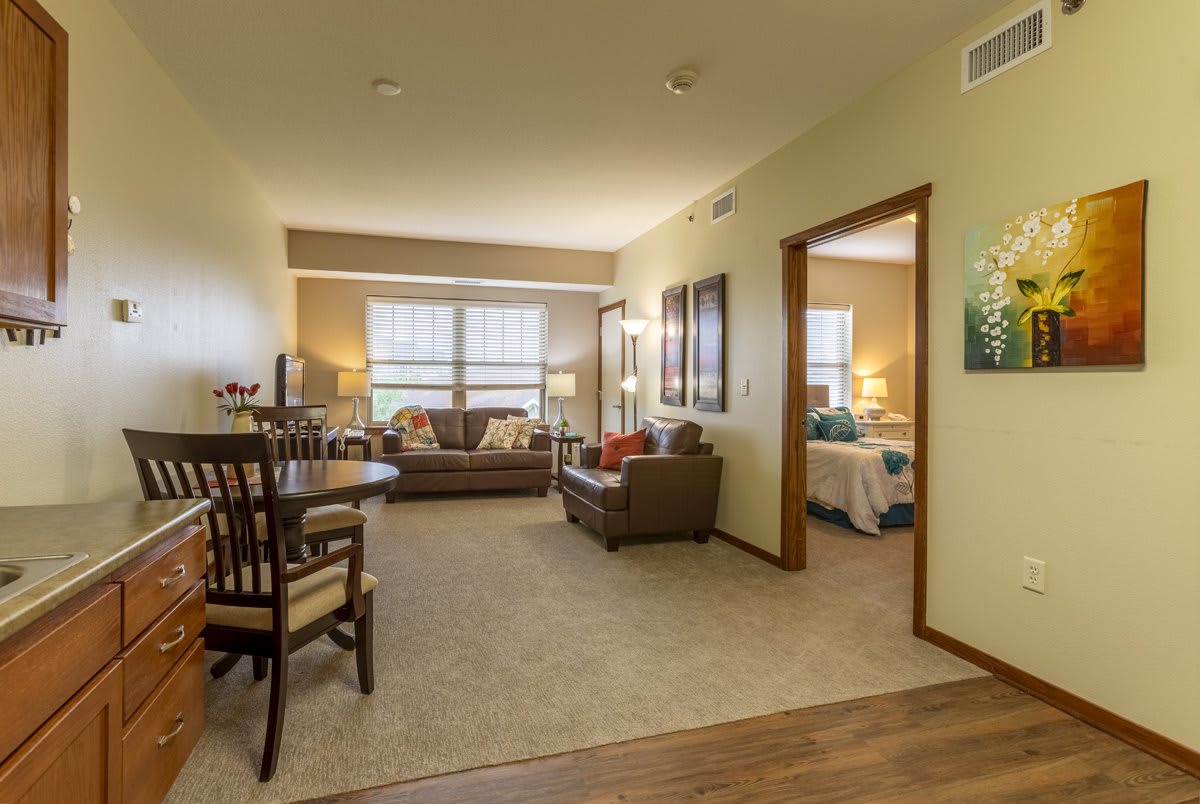 A cozy apartment living area with a dining table and view into the bedroom.