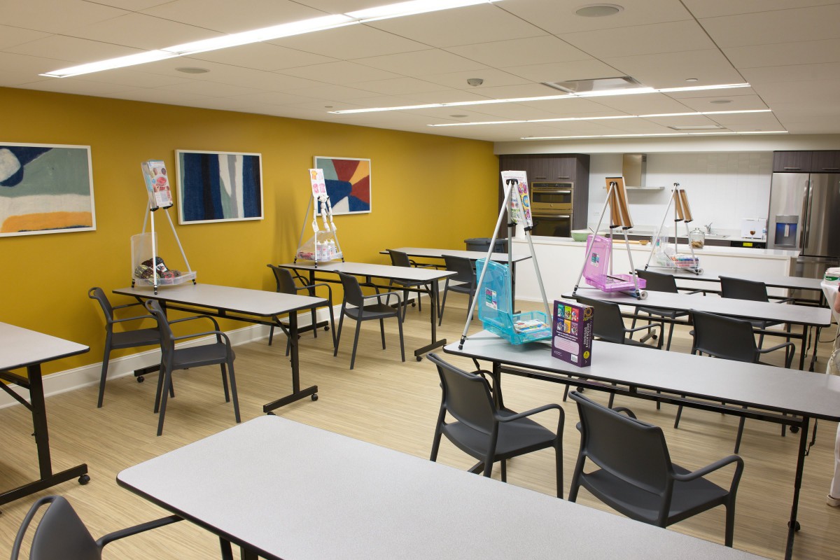 A brightly lit classroom with art easels and supplies set up for a painting session.