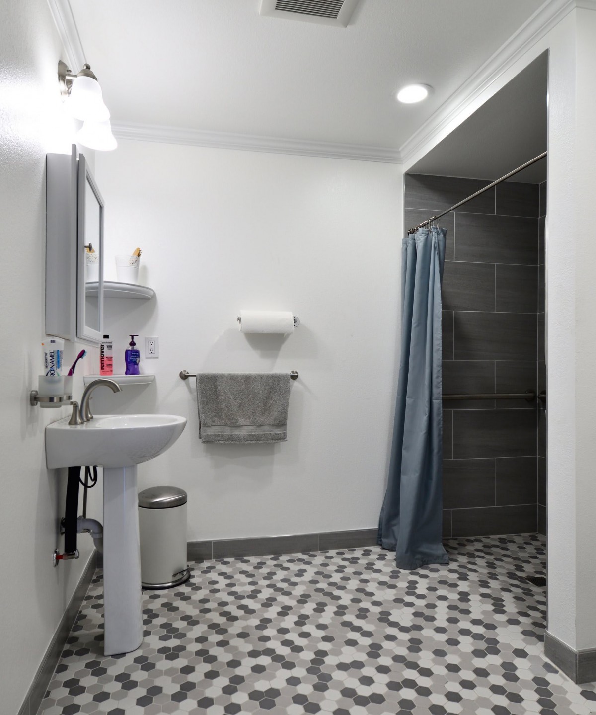 A modern bathroom with a sink, shower, and patterned tile flooring.