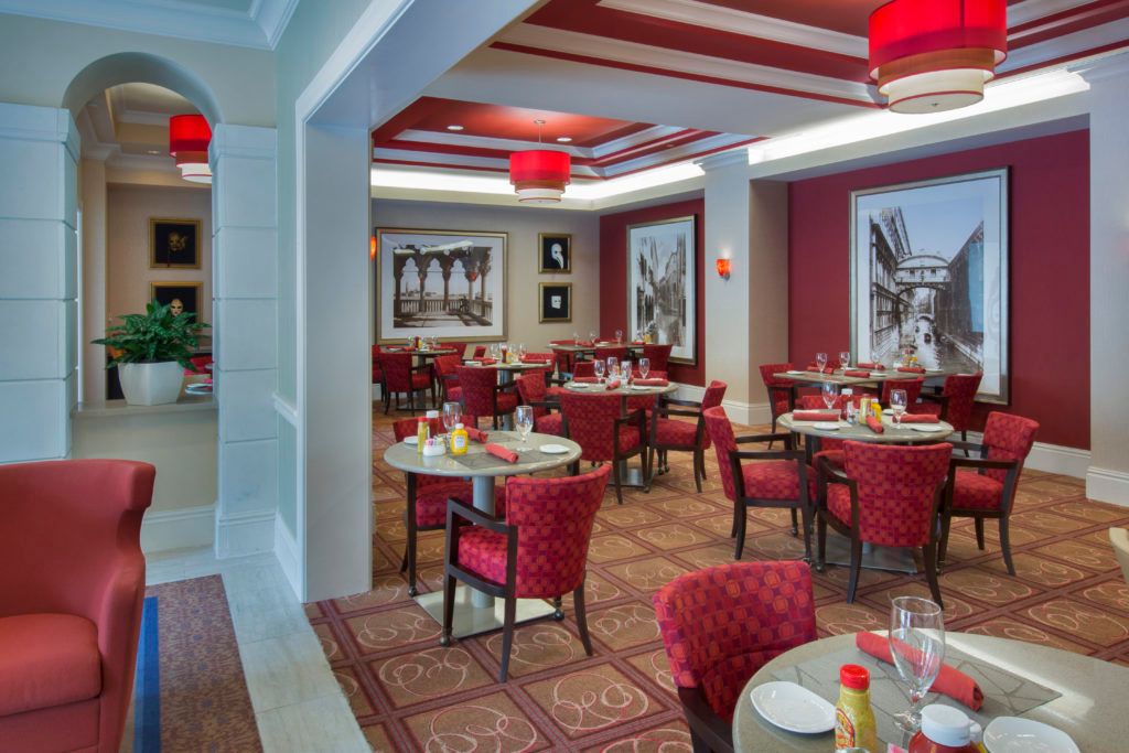 A stylish restaurant interior featuring red-accented decor and neatly arranged dining tables.