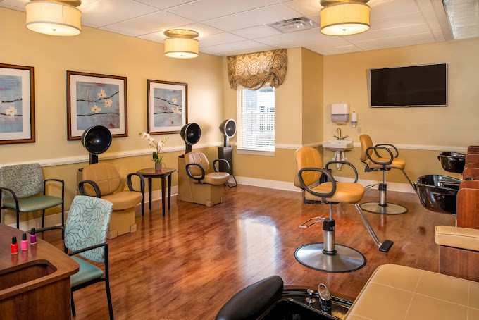 A cozy salon interior with chairs and hair dryers, featuring warm lighting and a wooden floor.