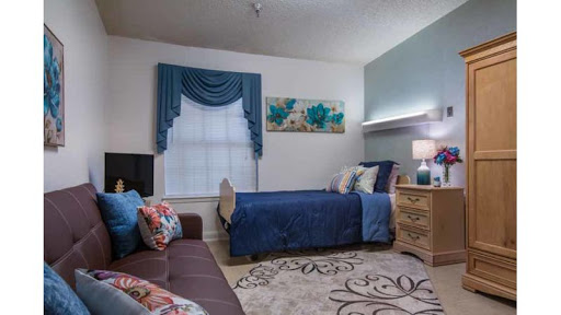 A cozy bedroom featuring a blue color scheme with floral accents and a comfortable seating area.