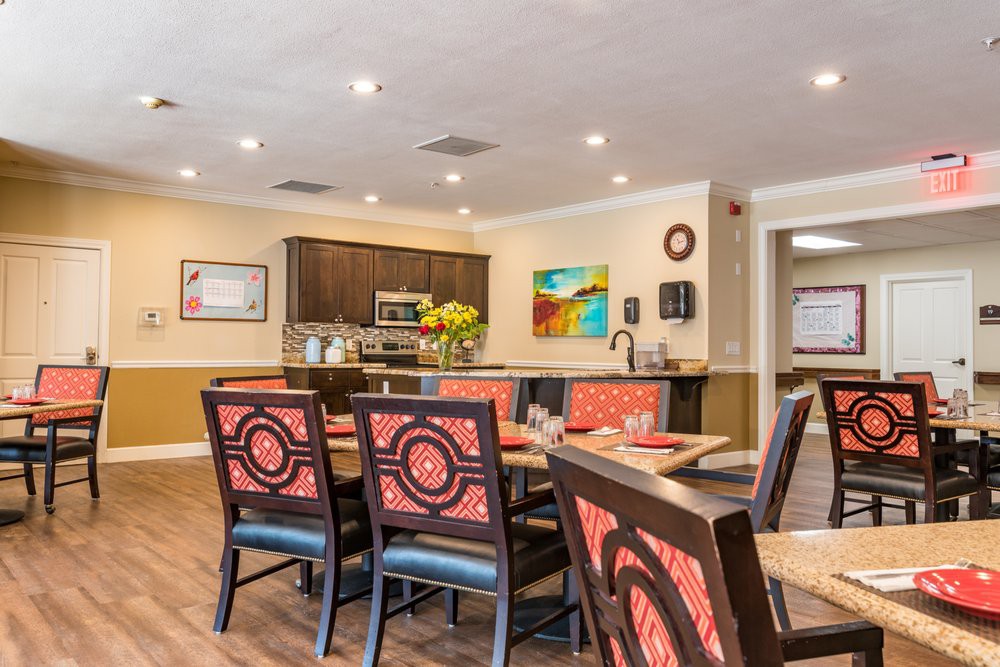 A modern dining area with stylish furniture and a kitchen in the background.