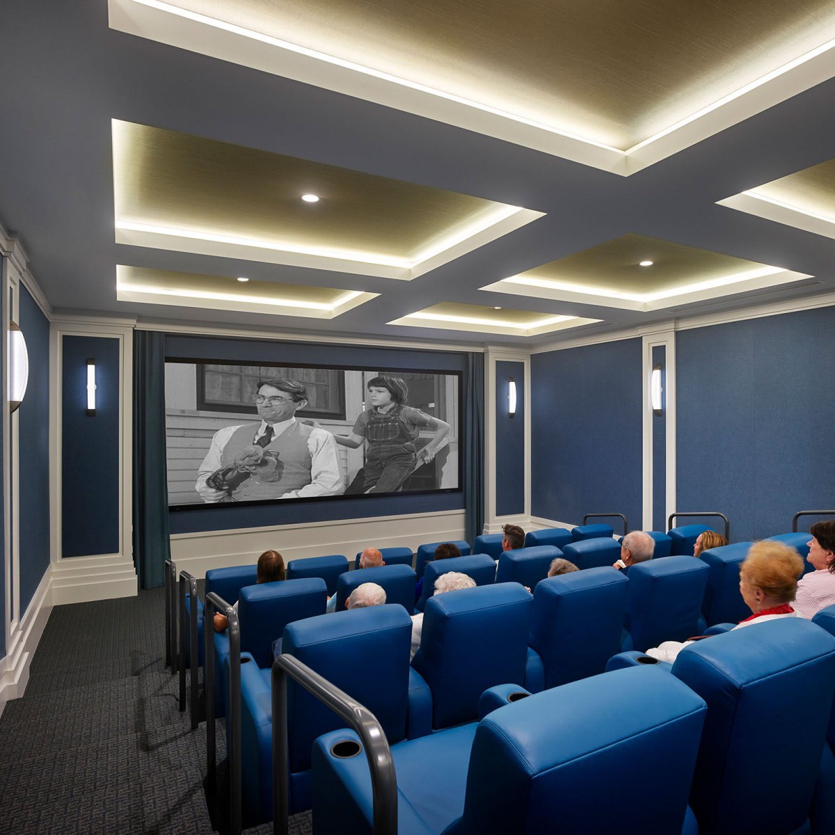 A home theater room with blue seating and a classic movie playing on the screen.