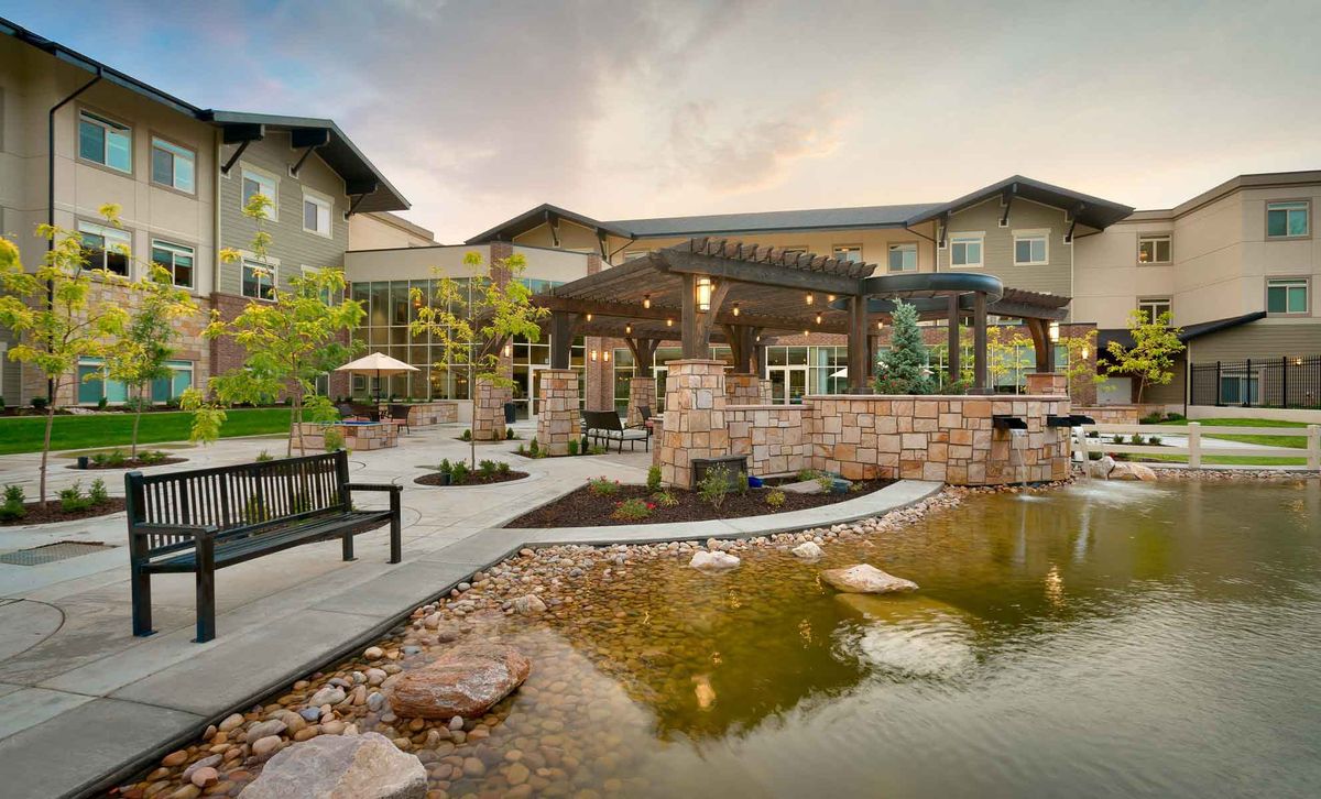 A serene outdoor patio area with a pond and garden landscaping in front of a modern building.