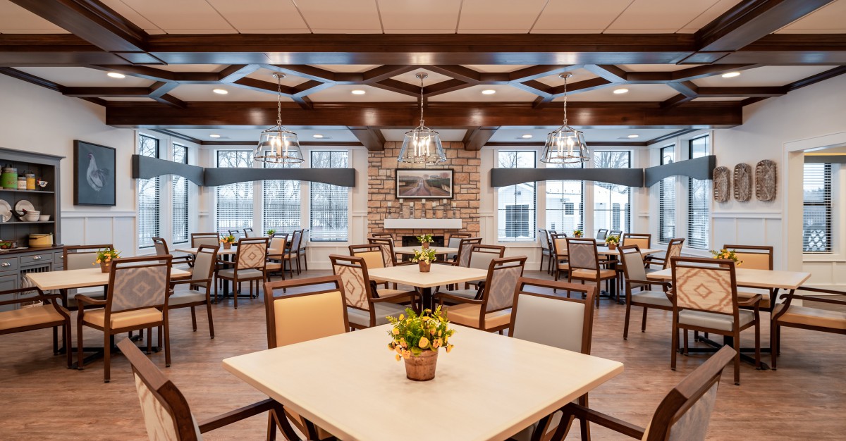 A spacious and elegantly designed dining room with neatly arranged tables and chairs, featuring large windows and modern lighting.