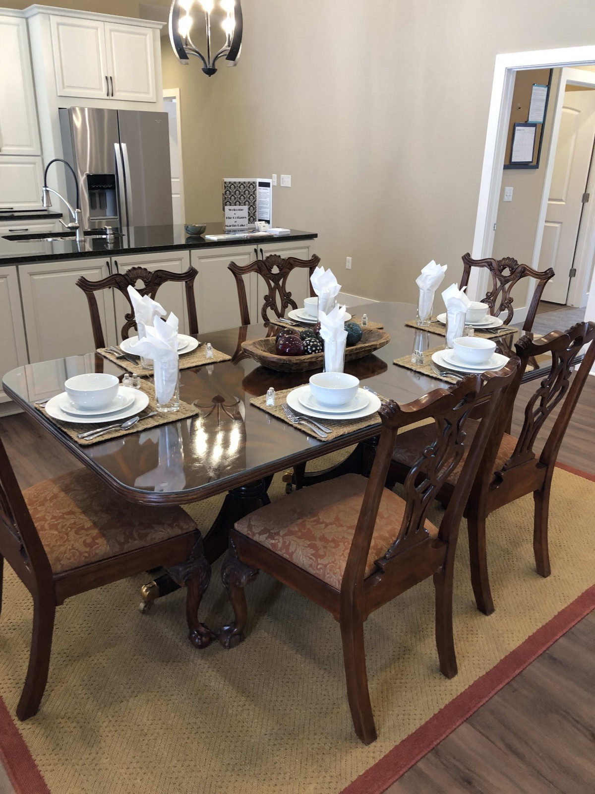 A dining area featuring a glass-top table set for six with elegant place settings and wooden chairs.