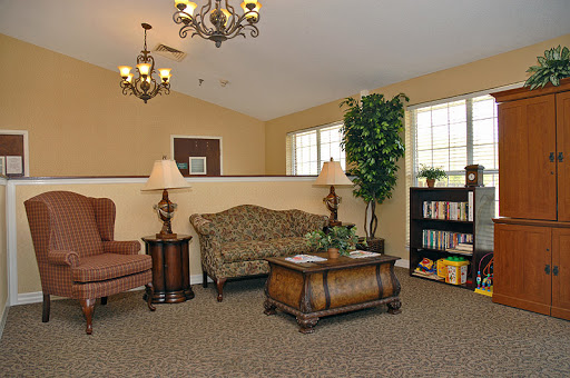 A cozy living room with comfortable furniture, warm lighting, and a bookshelf.