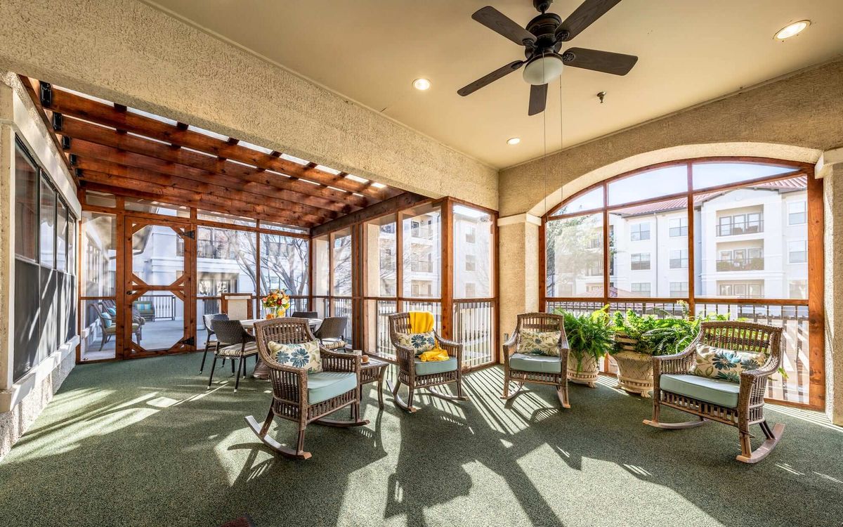 A cozy sunroom with comfortable seating, indoor plants, and large windows allowing natural light to fill the space.