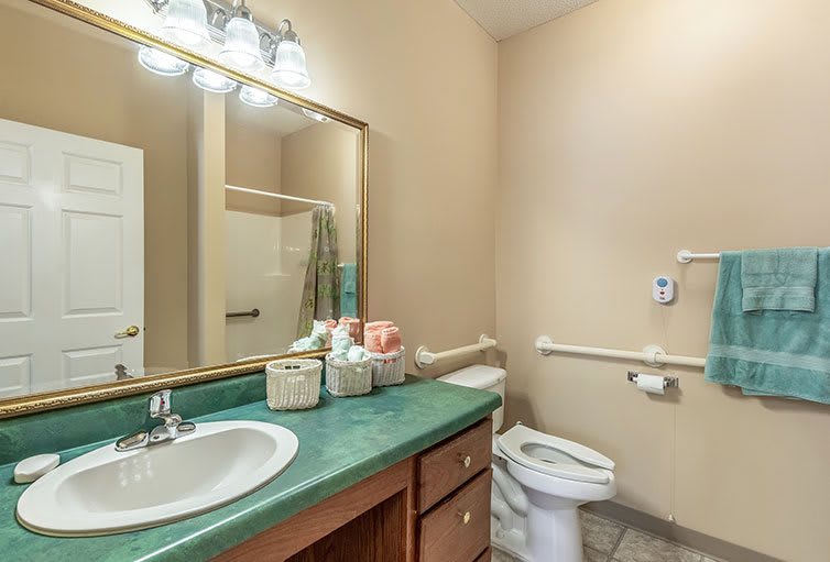A clean and simple bathroom with a green countertop and large mirror.