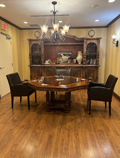 A well-furnished conference room featuring a round wooden table, black chairs, and an elegant chandelier.