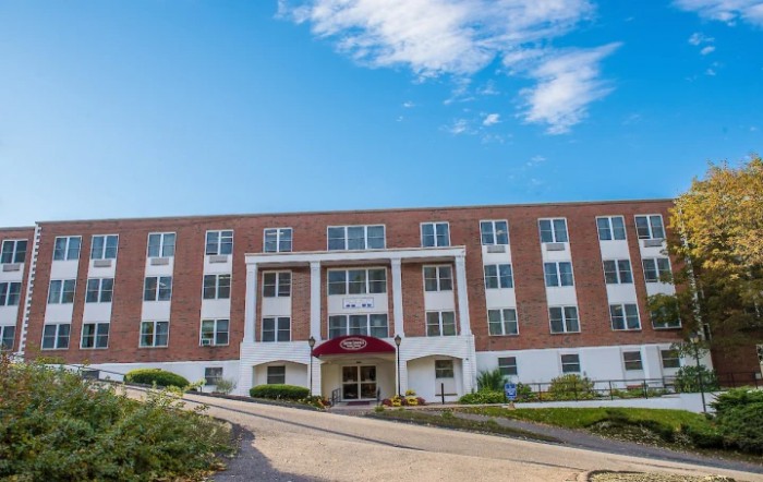 A brick residential building with a symmetrical facade under a partly cloudy sky.
