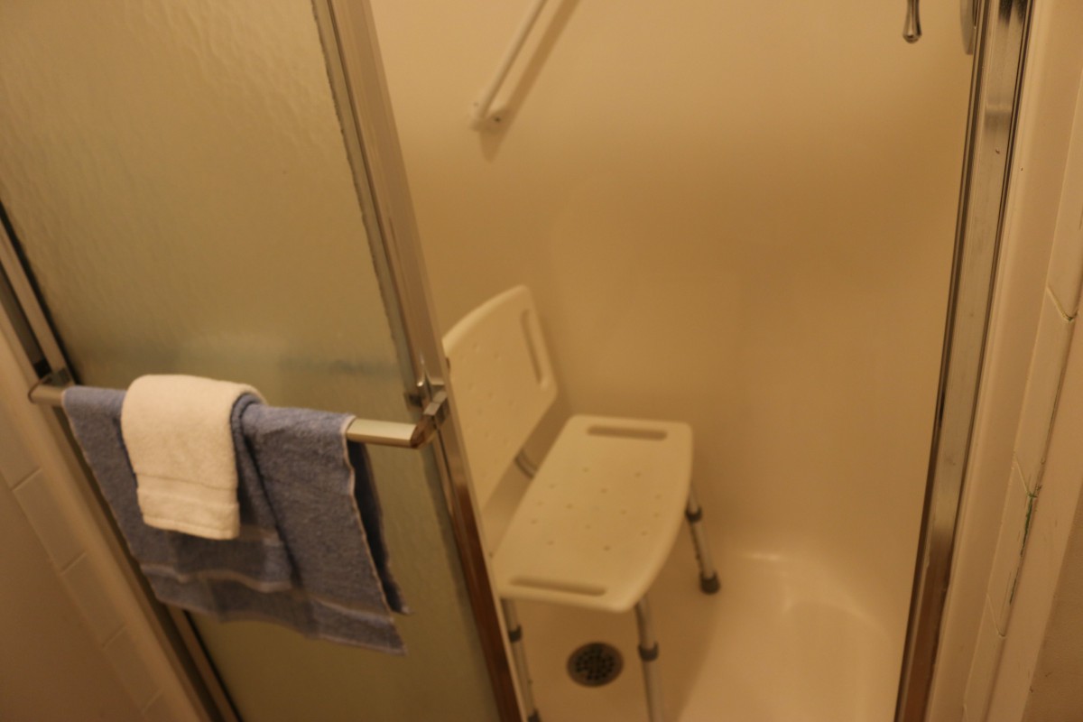 A shower area equipped with a shower chair and grab bar for accessibility.