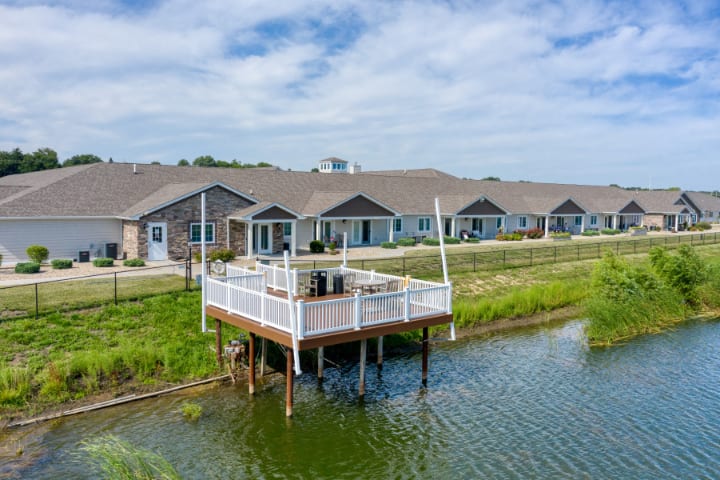 A series of waterfront residential buildings with a deck overlooking the lake under a cloudy sky.