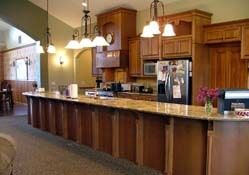 A spacious kitchen featuring wooden cabinetry, granite countertops, and modern pendant lighting.