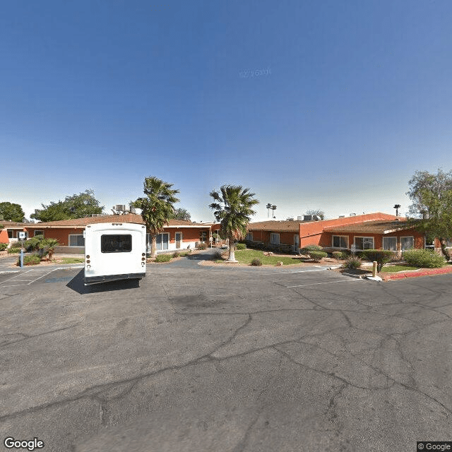 A roadside motel with a parked vehicle in a desert landscape under a clear blue sky.
