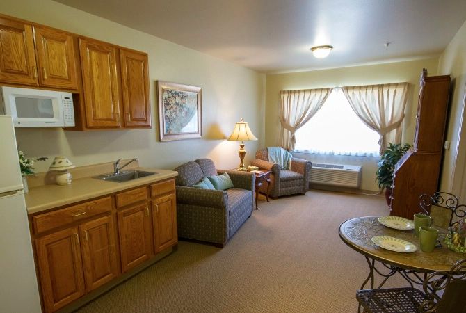 A cozy living room with comfortable seating, natural light, and wooden cabinetry.