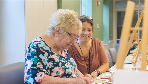 Two women engaging in a creative activity at a community event.